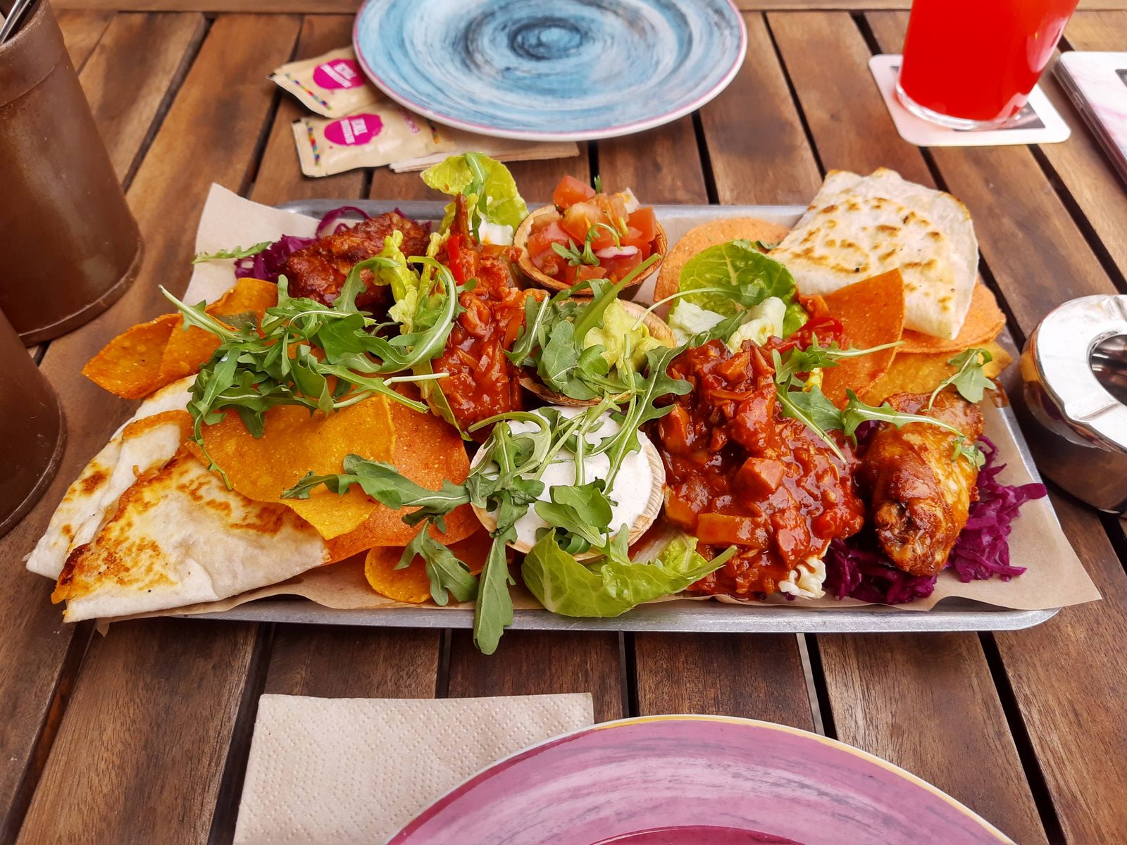 Teller mit Fladenbrot, Salat und Dips auf einem Holztisch